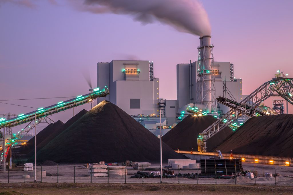 Coal-fired power plant at dusk with conveyors and fuel piles